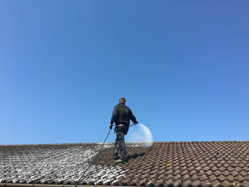 Technician soft-washing a clay tile roof