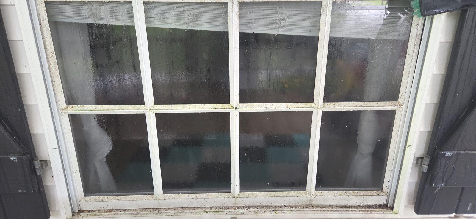 Before: window between black shutters with dirty, spotted glass