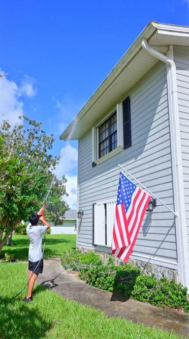 Seatown crew soft washing the siding of a two-story home