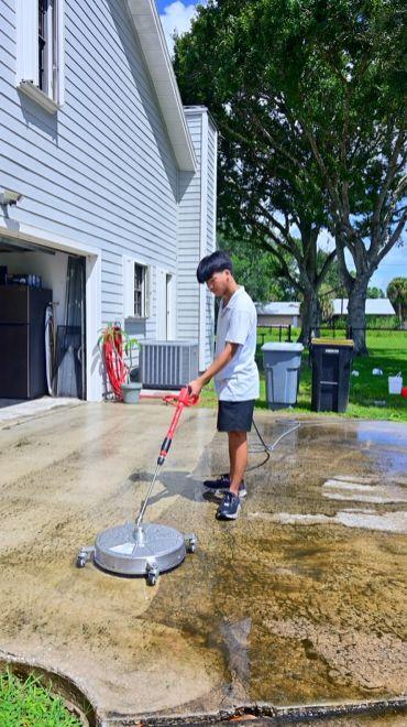 Seatown crew member pressure washing a driveway with a surface cleaner