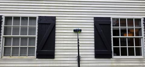 Water-fed pole cleaning the windows of a sided home